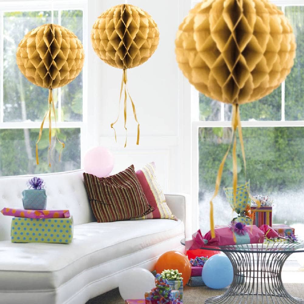 Drie gouden honeycombs in een kamer met cadeaus en ballonnen