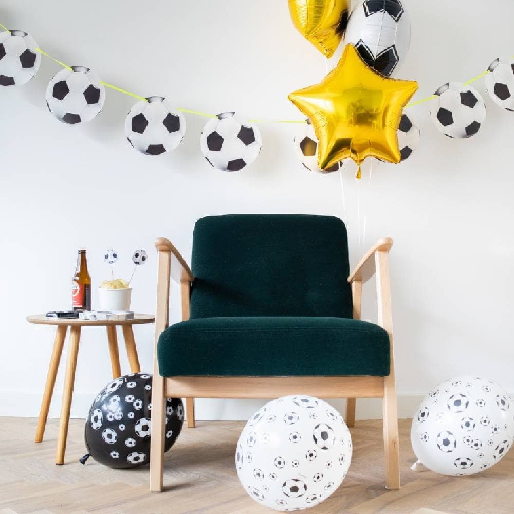 Voetbalslinger in kamer met voetbalballonnen en groene stoel
