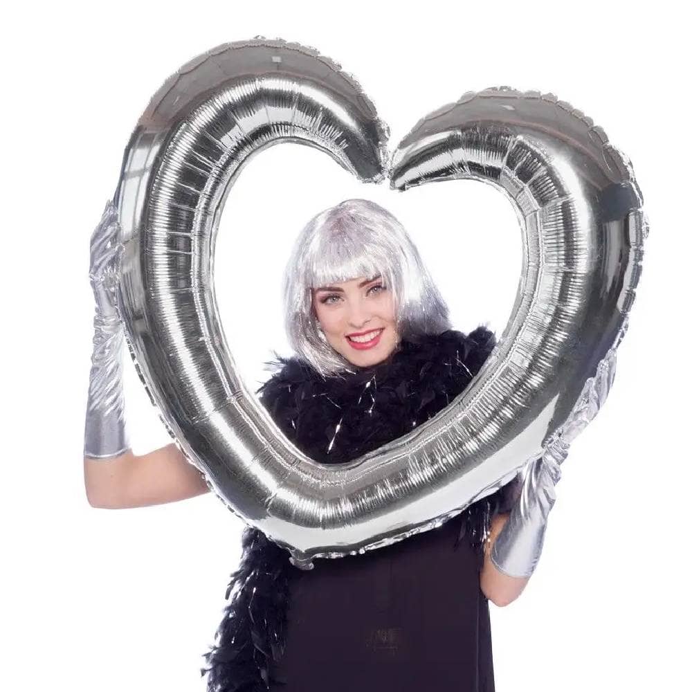 Vrouw met zilveren pruik poseert met hartvormig folieballon frame