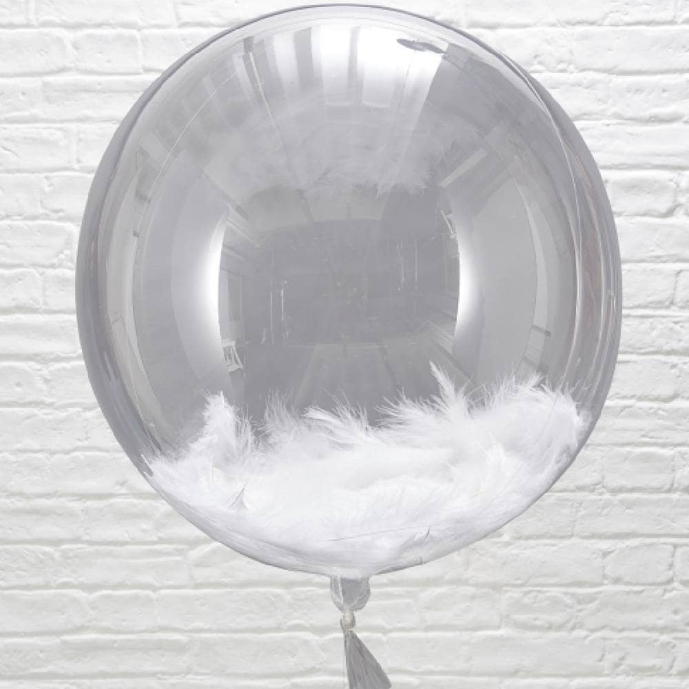 Grote transparante ballon gevuld met witte veren voor witte muur