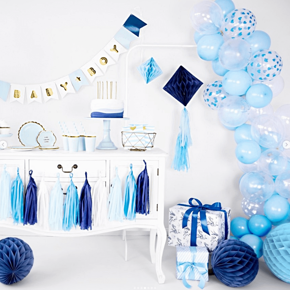 versiering voor een babyshower in het blauw met honeycomb, een tasselslinger en een lichtblauwe ballonnenboog
