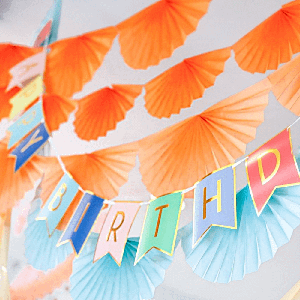 Slinger happy birthday met gouden details hangt onder een slinger met oranje waaiers