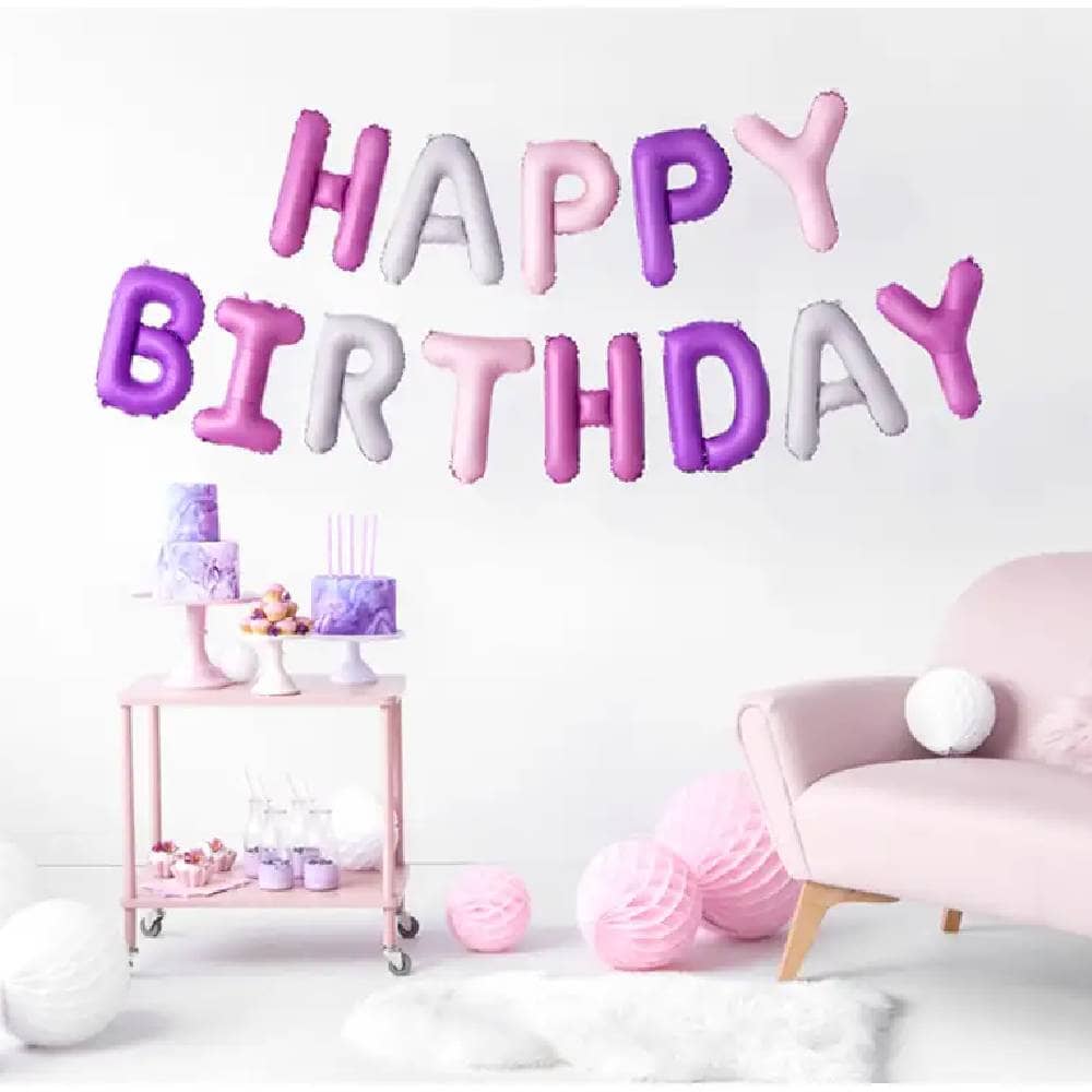 Kamer met tafeltje met taarten een bank en honeycombs op de grond en Happy birthday folieballon