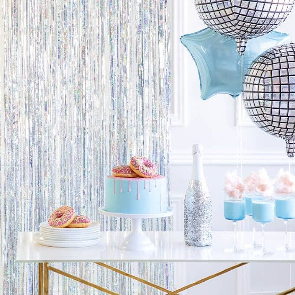 Tafel met conuts taart en champagne met holografische backdrop en disco ballonnen