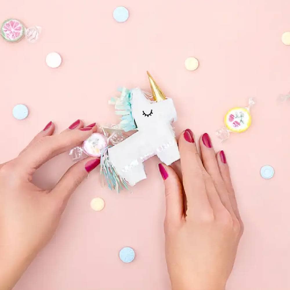 Twee handjes met een mini pinata in de vorm van een unicorn