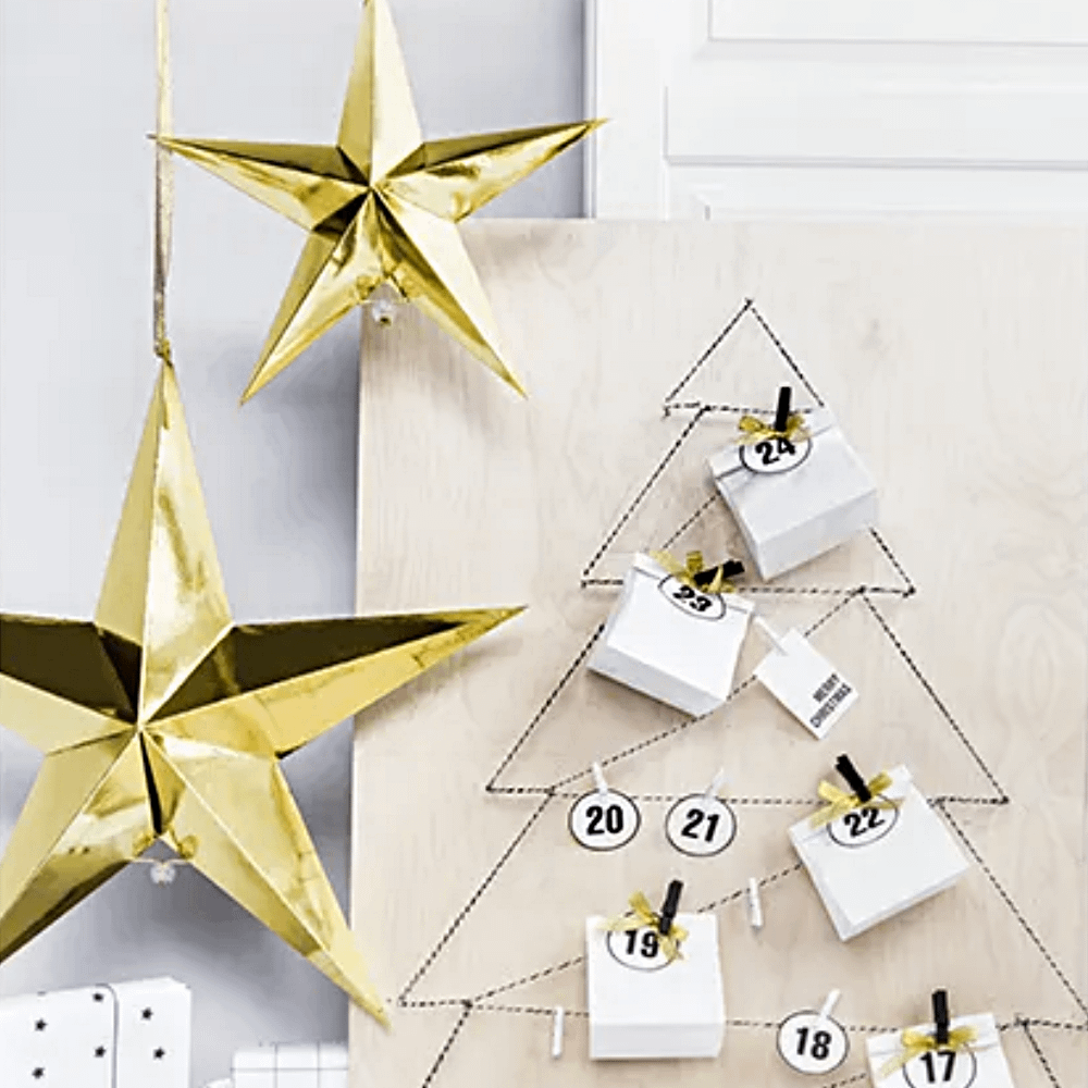 Gouden sterren hangen naast een papieren kerstboom