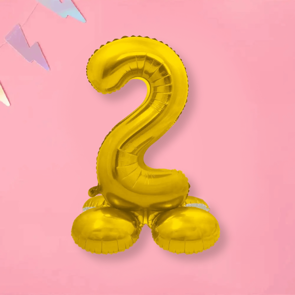 Folieballon cijfer 2 in de kleur goud op standaard op een roze achtergrond