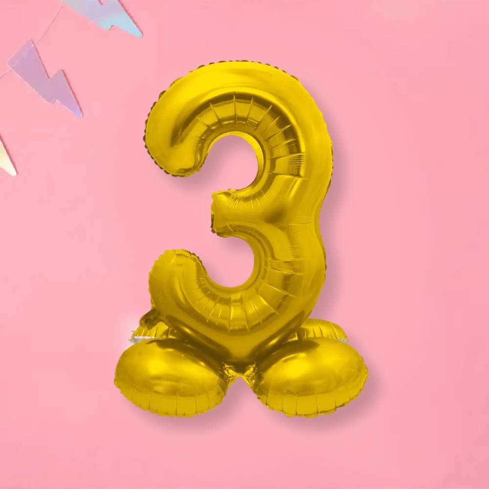 Folieballon op standaard cijfer 3 in de kleur goud op een roze achtergrond met slinger in pasteltinten