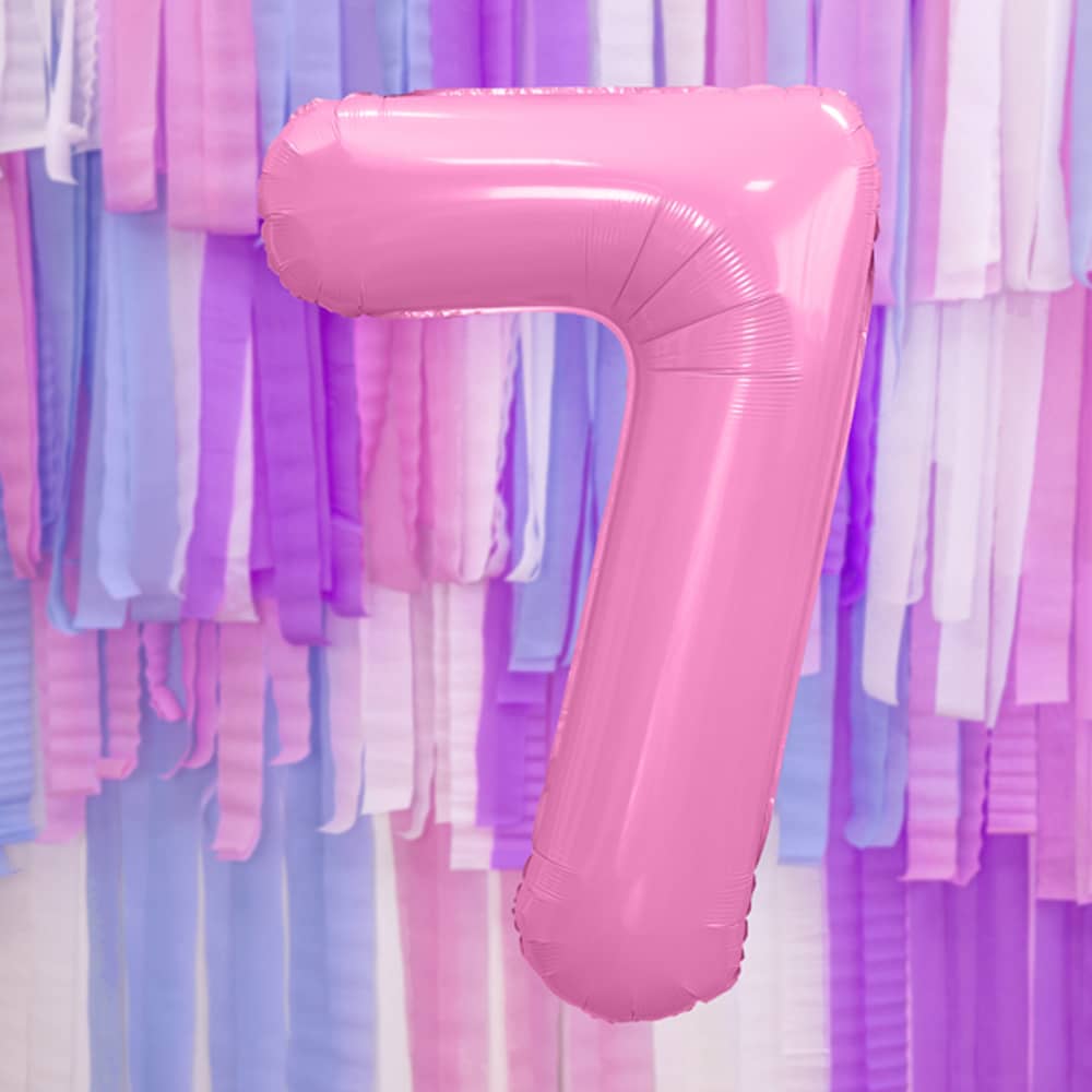 Folieballon cijfer 7 in de kleur roze voor een muur bedekt met paarse, witte, blauwe en roze franjes