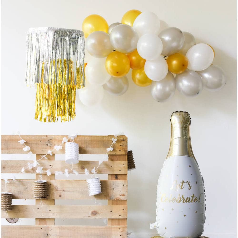 Muur met ballonnen en franje versiering en champagne vormige folieballon en versierde pallet
