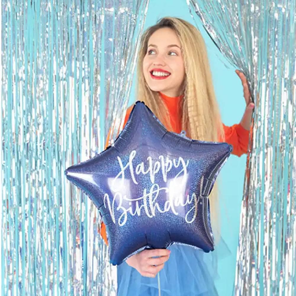 Vrouw tussen zilveren backdrop met donkerblauwe foliester met happy birthday erop