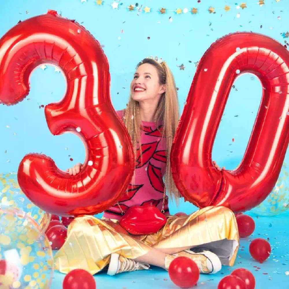 Vrouw houd twee rode ballonnen vast in de cijfers 3 en 0