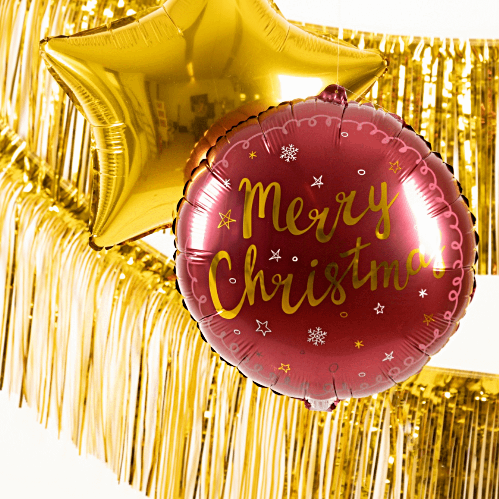 Gouden franje slinger hangt achter een gouden ballon van een ster en een rode kerstballon