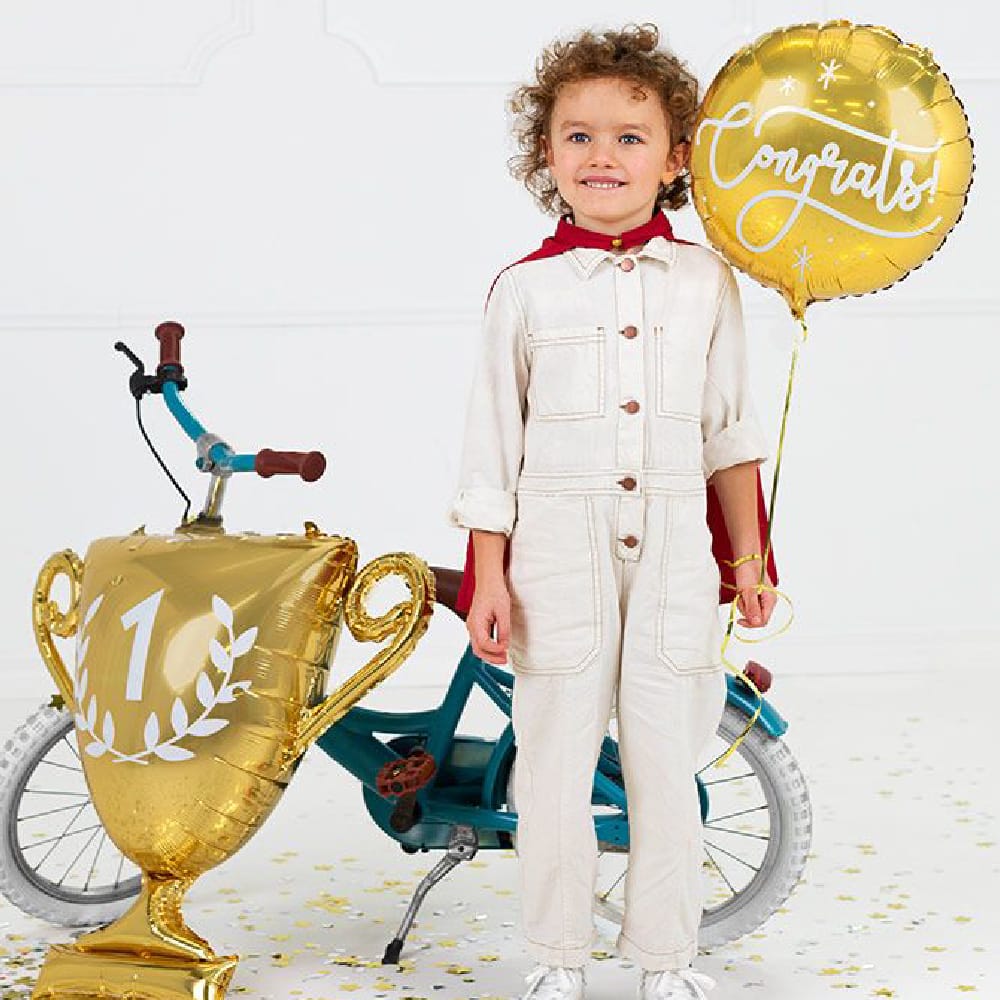 Jongetje in witte overall met gouden ballonnen voor een groene fiets