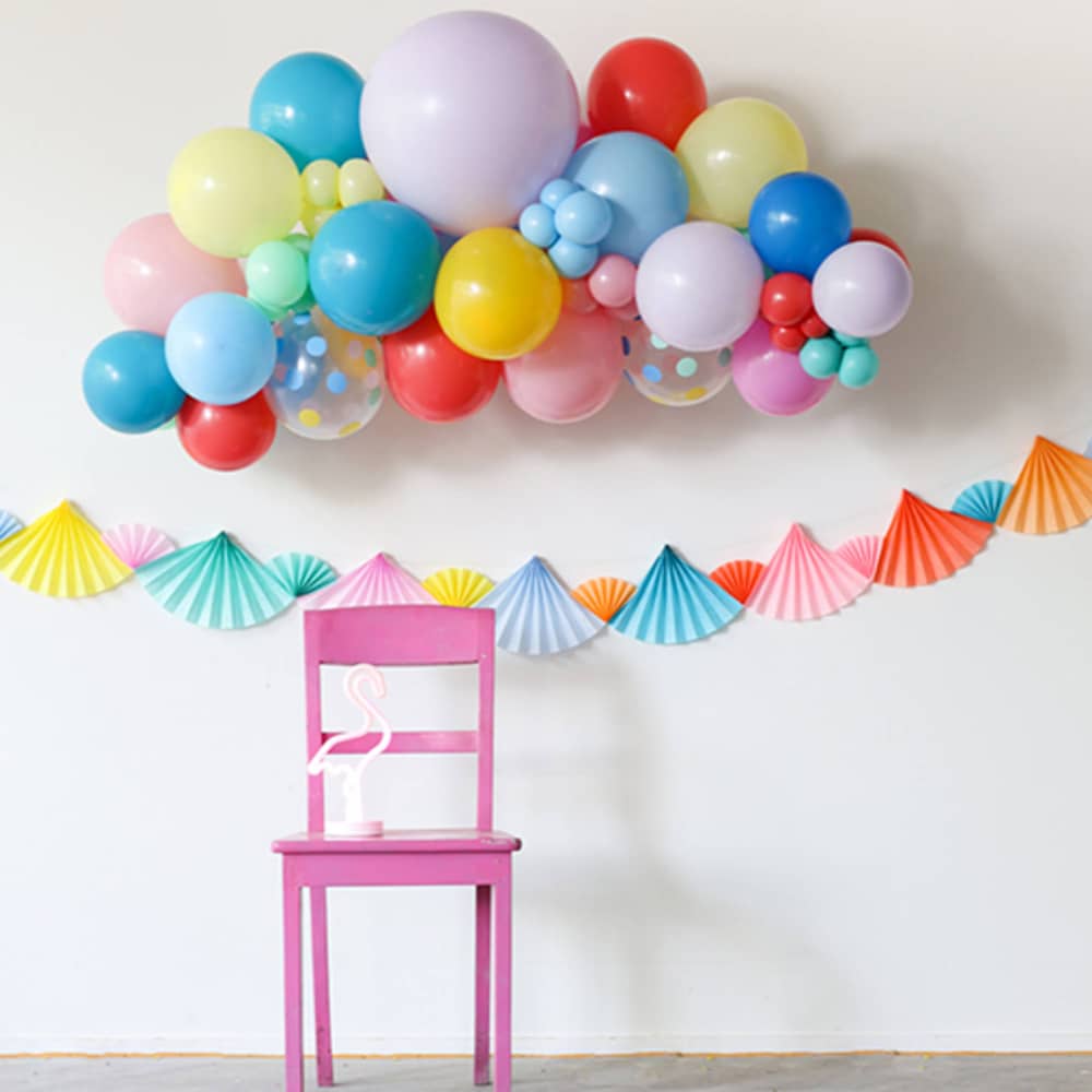 Waaiers aan een lijntje en een ballonnenversiering met een roze stoel