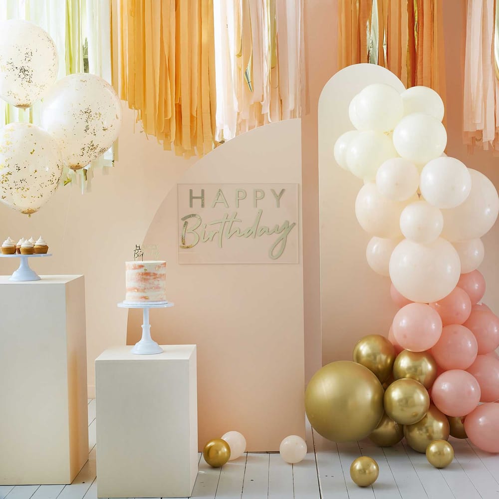 kamer met perzikkleurige en goudkleurige verjaardagsversieringen