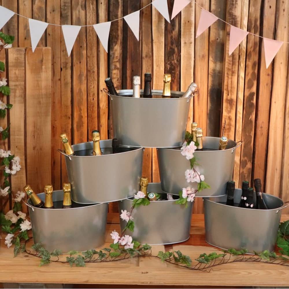 zes champagne emmers opgestapeld met kunstbloemen voor een houten paneel