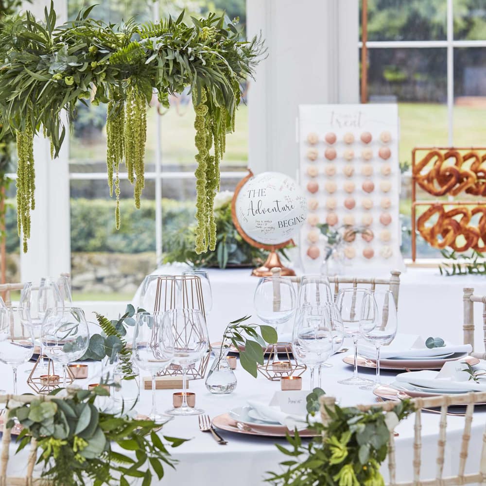 Gedekte tafel voor bruiloft met wereldbol en groene decoratie