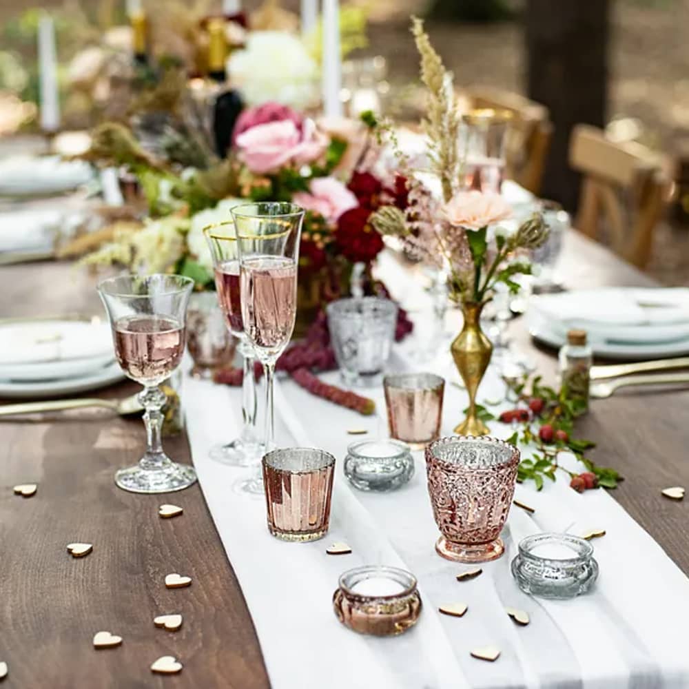 Gedekte tafel met glazen, bloemen waxinelichthouders en houten hartjes