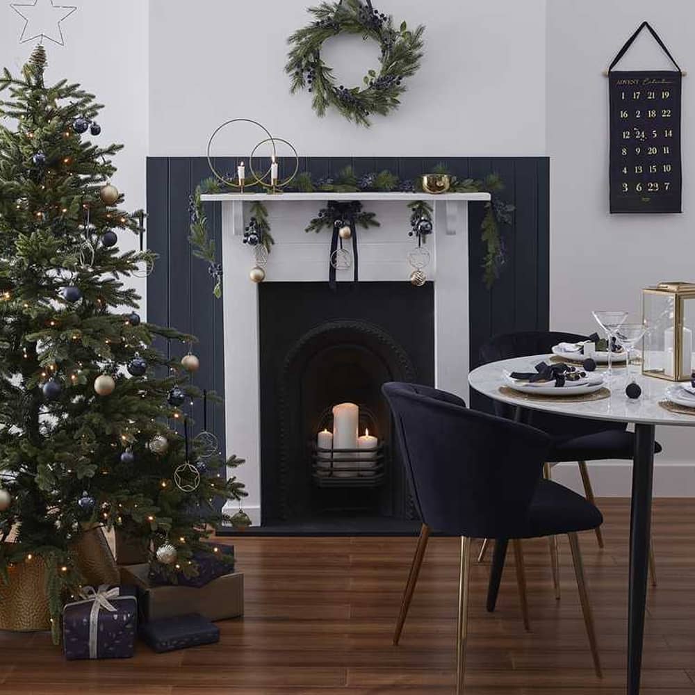 Stijlvolle kamer met schouw waar kaarsen in staan, een gedekte tafel en diverse kerstdecoratie