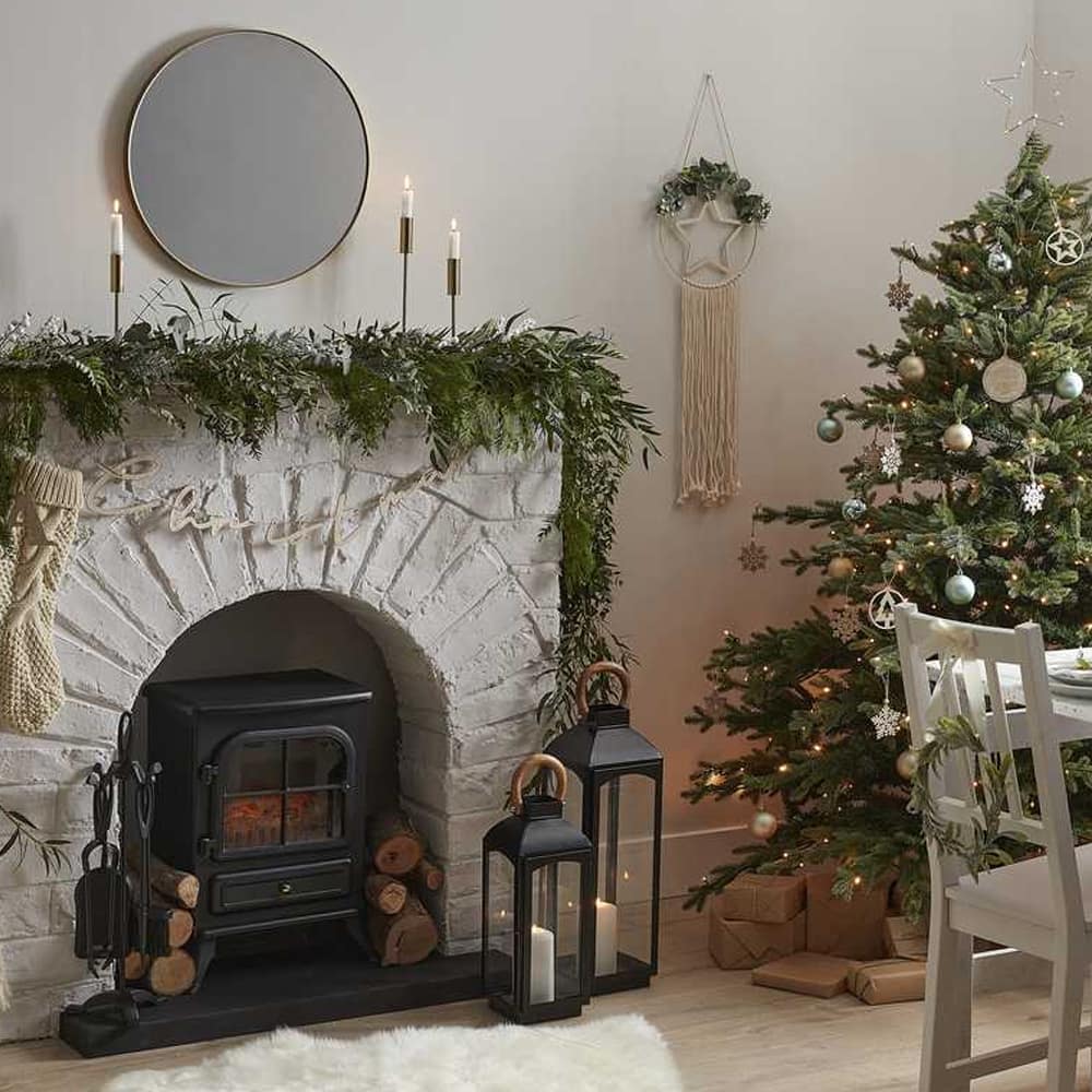 Kamer met houthaardje, kerstboom en groen op de schouw