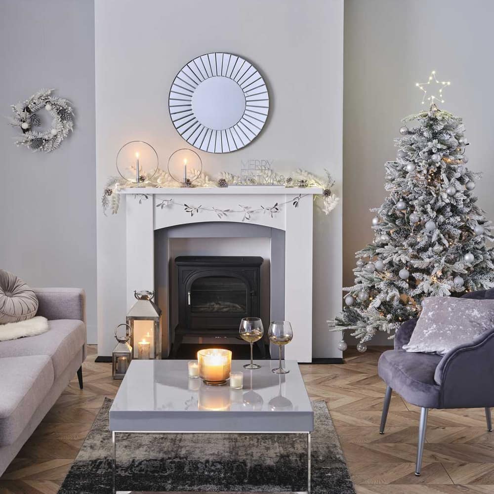 Kamer gedecoreert voor kerst met een witte kerstboom en witte en zilveren versiering
