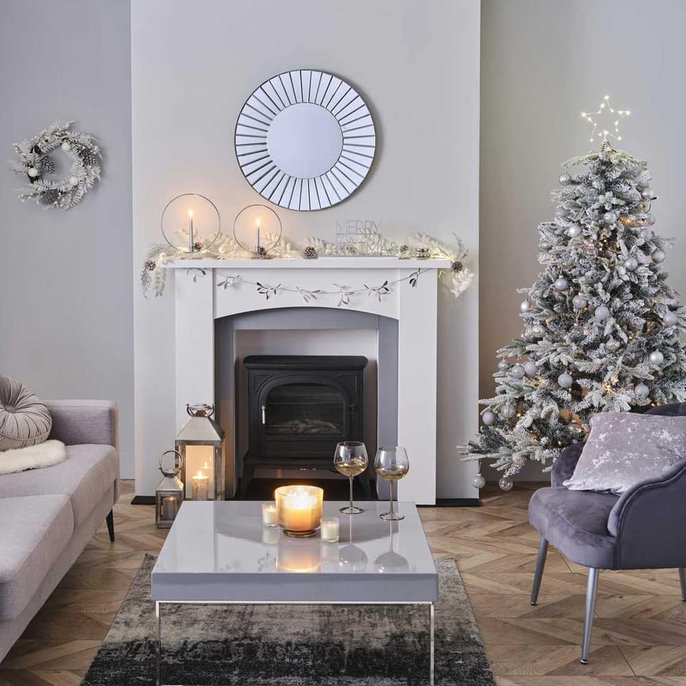 Kamer gedecoreert voor kerst met een witte kerstboom en witte en zilveren versiering