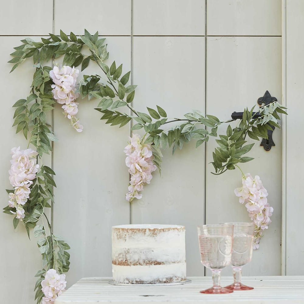 Tafel met taart en twee glazen en wand met bloemen streng