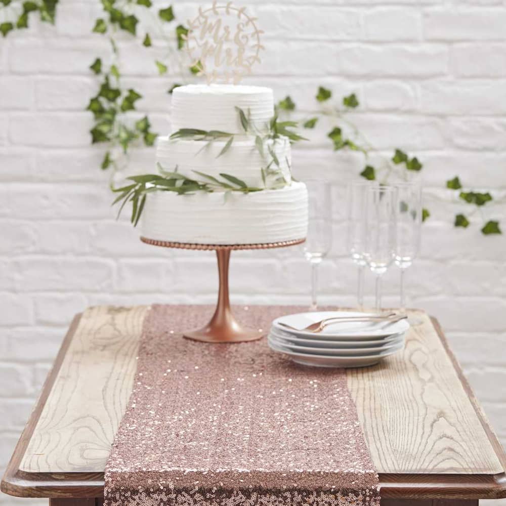 Tafelloper van rosé gouden pailletten met gebaksbordjes en een taart erop
