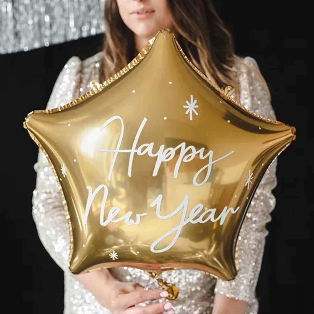 Vrouw met happy new year folieballon in de vorm van een ster