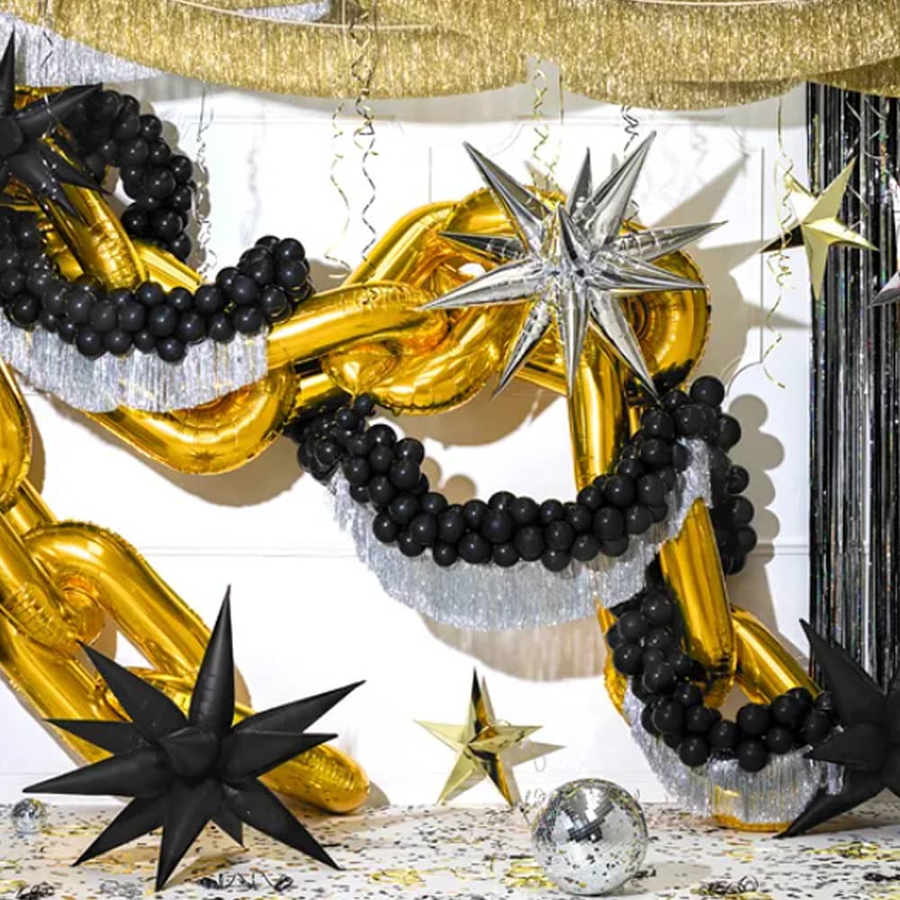 Kamer met zwarte ballonnen en gouden en zilveren slinger versiering en discobal op de grond