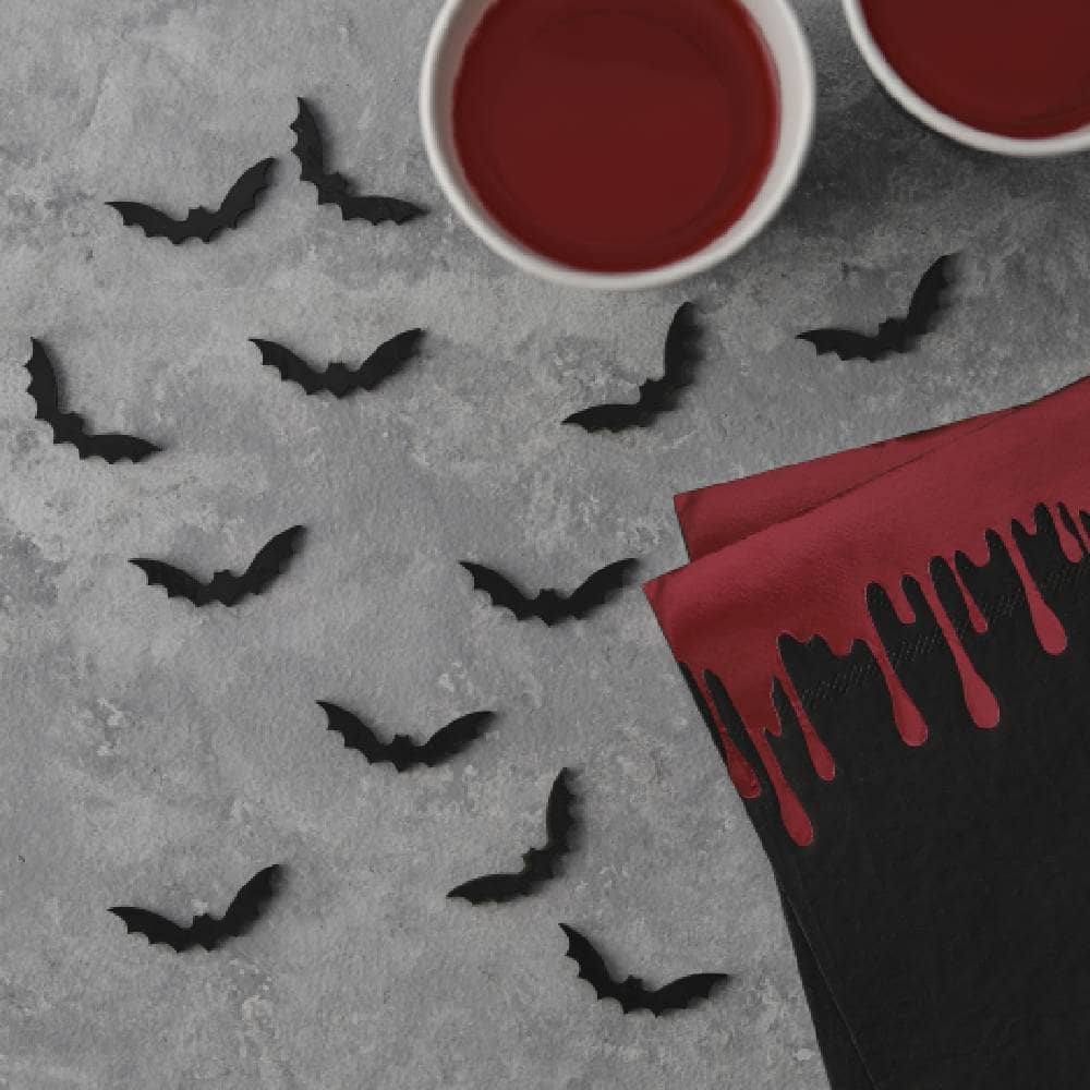 confetti in de vorm van vleermuizen op een grijze tafel met servetten en bekers