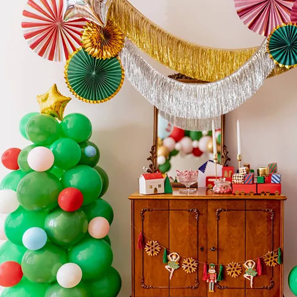 Versierde kamer met slingers waaiers en een kerstboom van ballonnen