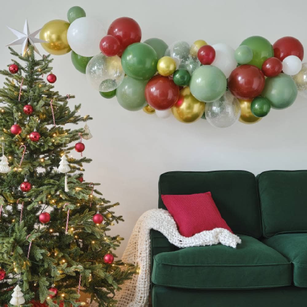 woonkamer met kerstboom groene bank en een ballonnenboog