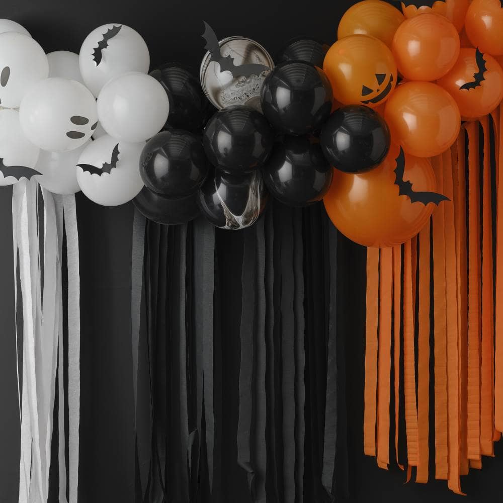 Halloween ballonnenboog met papieren vleermuizen erop en crepe slingers eronder voor zwarte muur