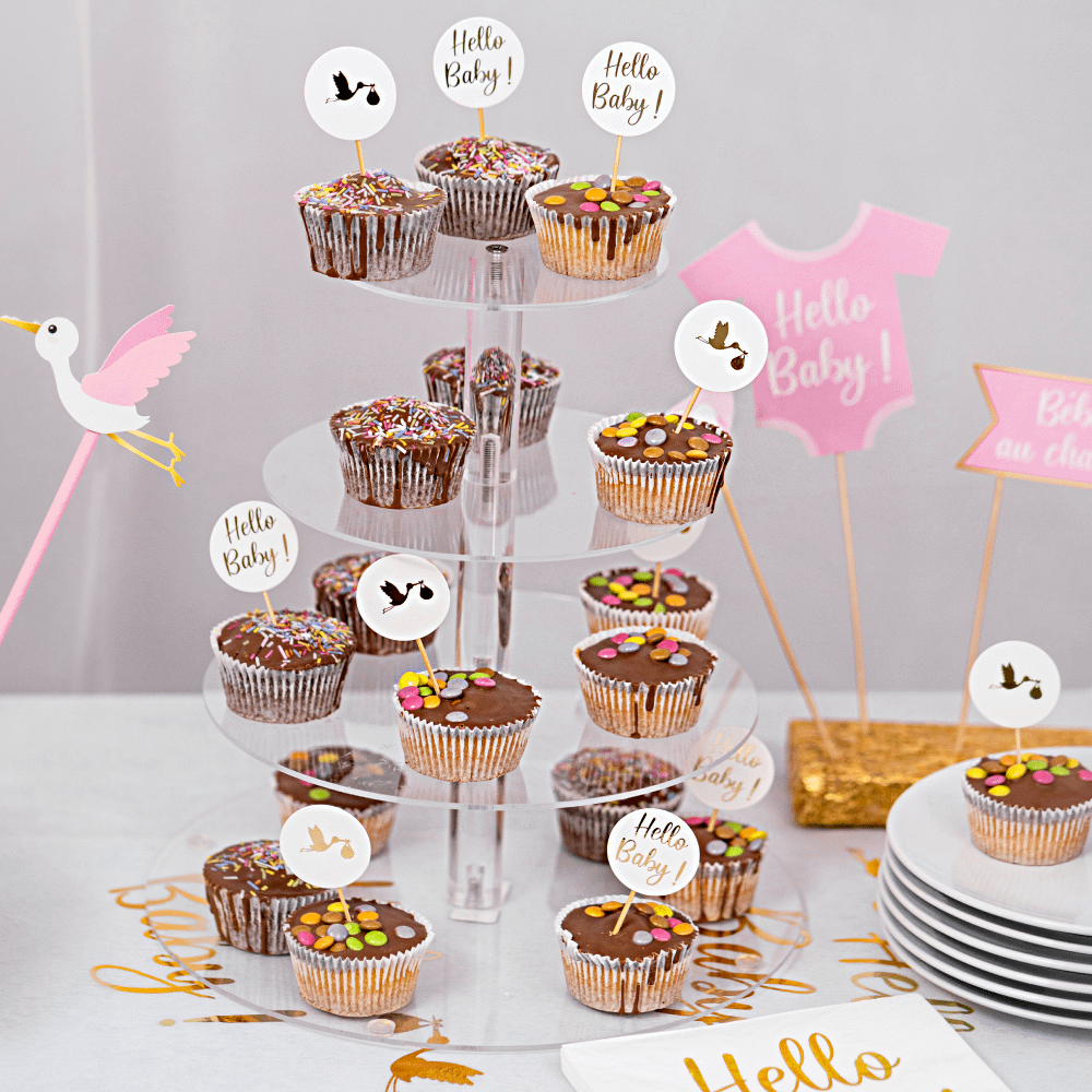 Transparante cupcake standaards met chocolade cupcakes en prikkers met de gouden tekst hello baby