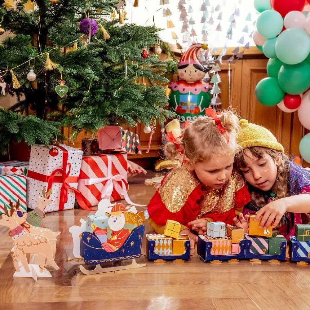 Kinderen bij advent kalender voor kerstboom pakken cadeautje uit
