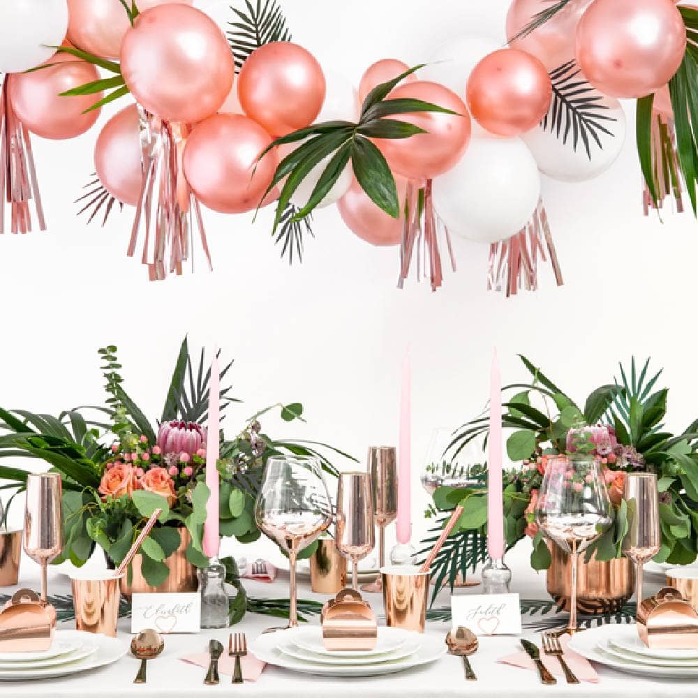 Versierde tafel met planten en rosé gouden tafeldecoratie en ballonnen