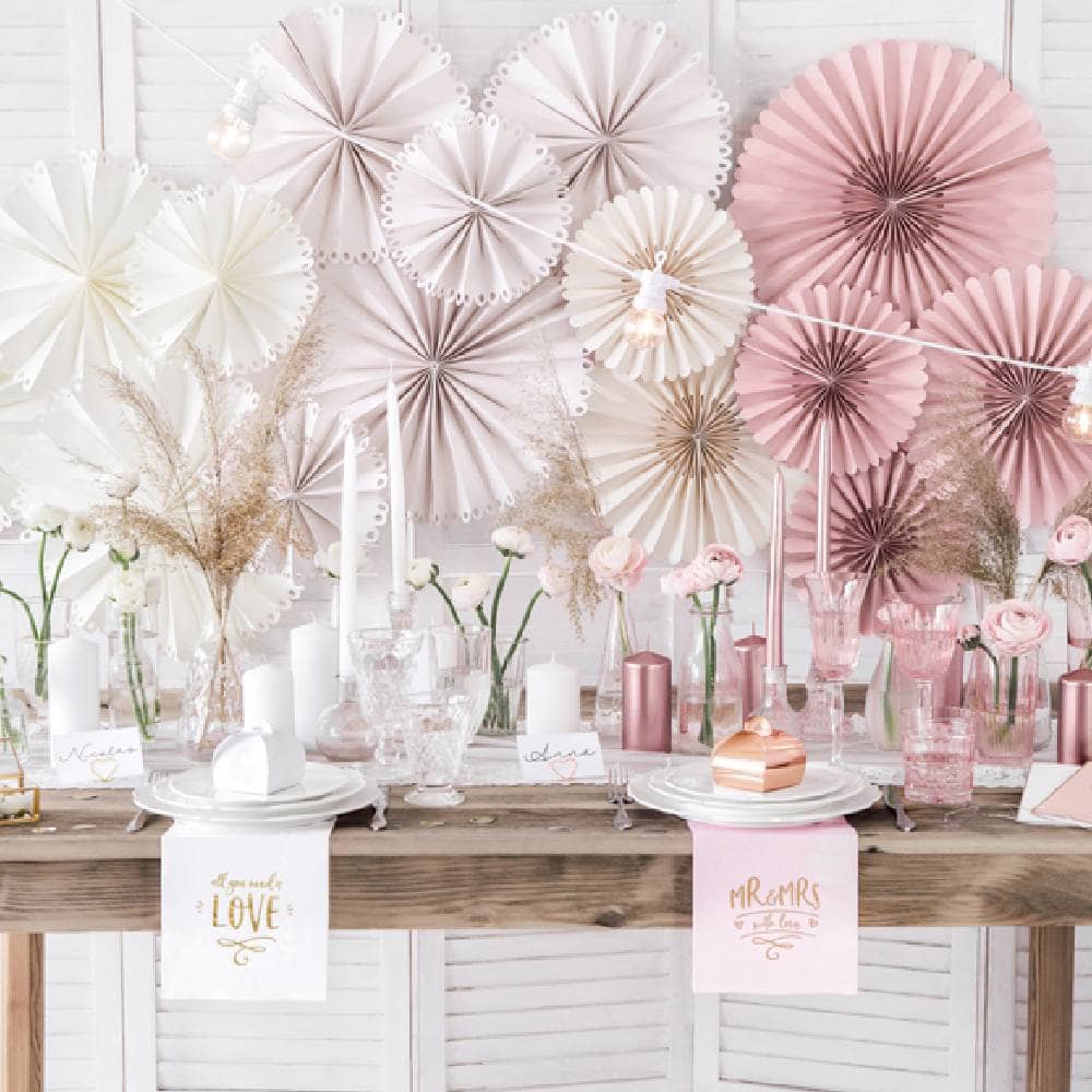 Versierde tafel met versierde wand vol witte en roze waaiers