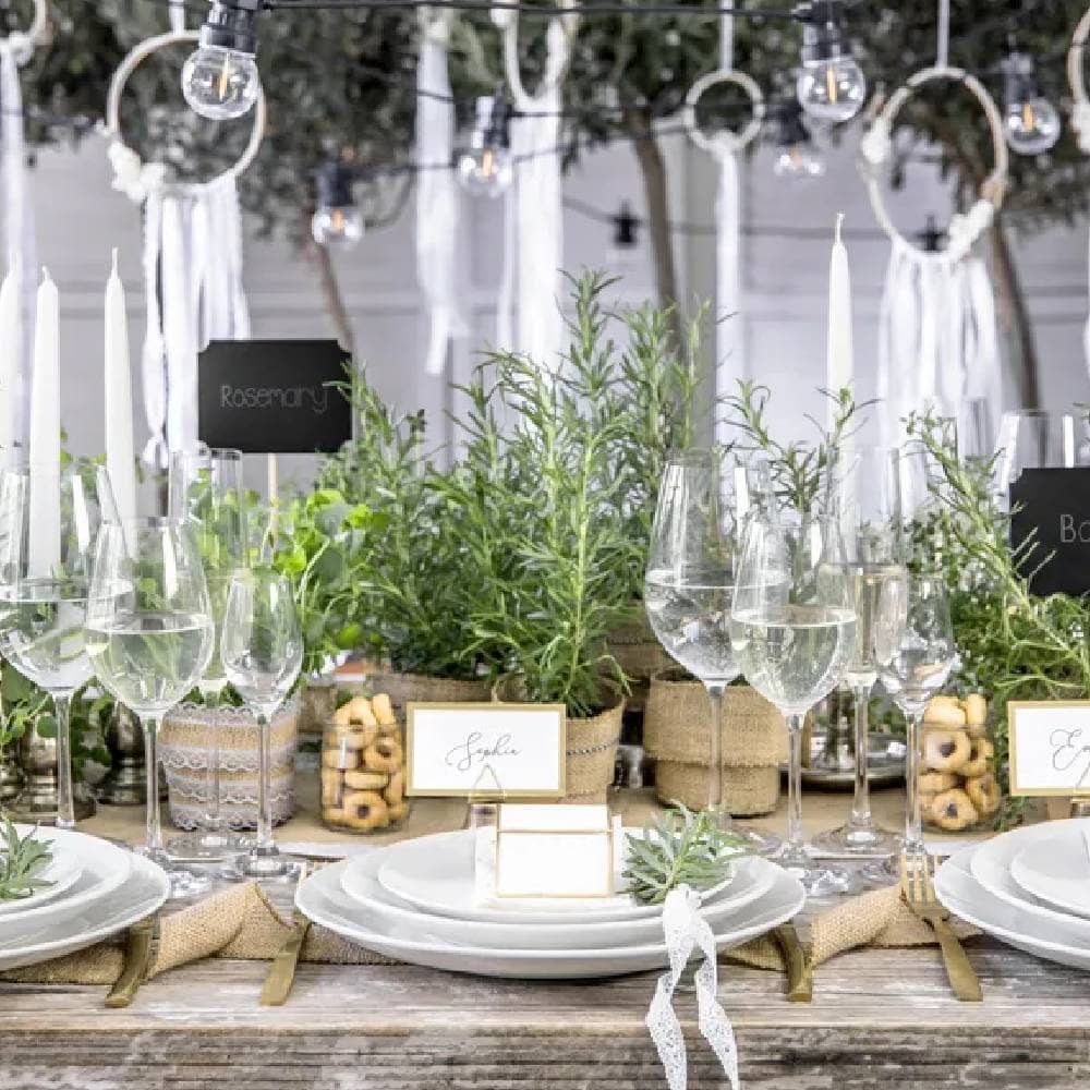 Versierde tafel met groene planten wijnglazen en witte borden