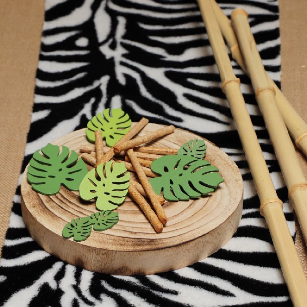 Houten plateau staat op een tafelloper met zebraprint en is versierd met groene bladeren en houten stokjes