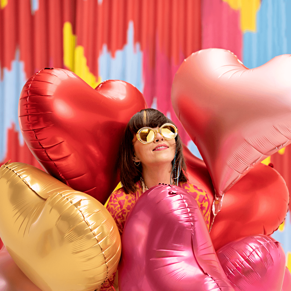 Vrouw met hartvormige ballonnen in het roze, rood en goud