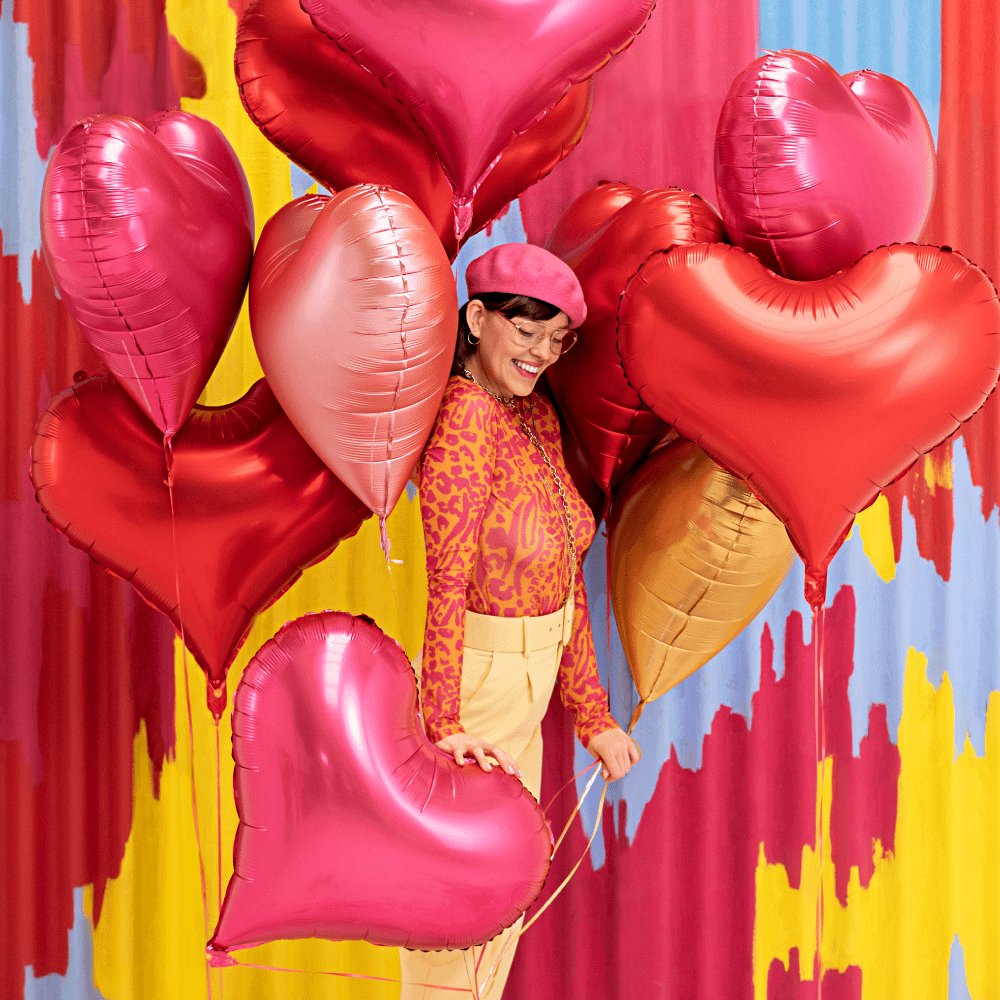 Vrouw met hartvormige ballonnen in het roze, rood en goud