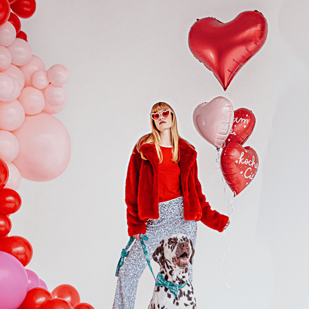 Vrouw met hond en een rode folieballon in de vorm van een hart