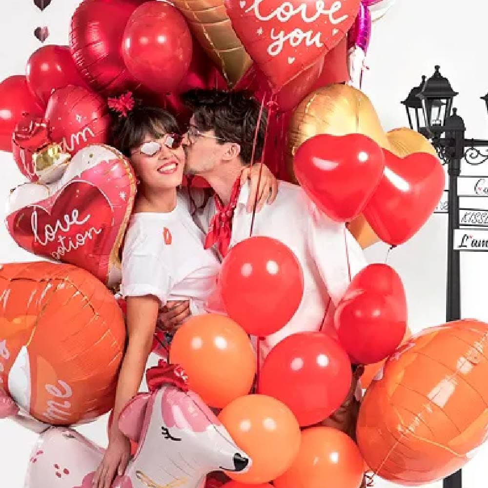 Man kust vrouw op de wang omringd door ballonnen