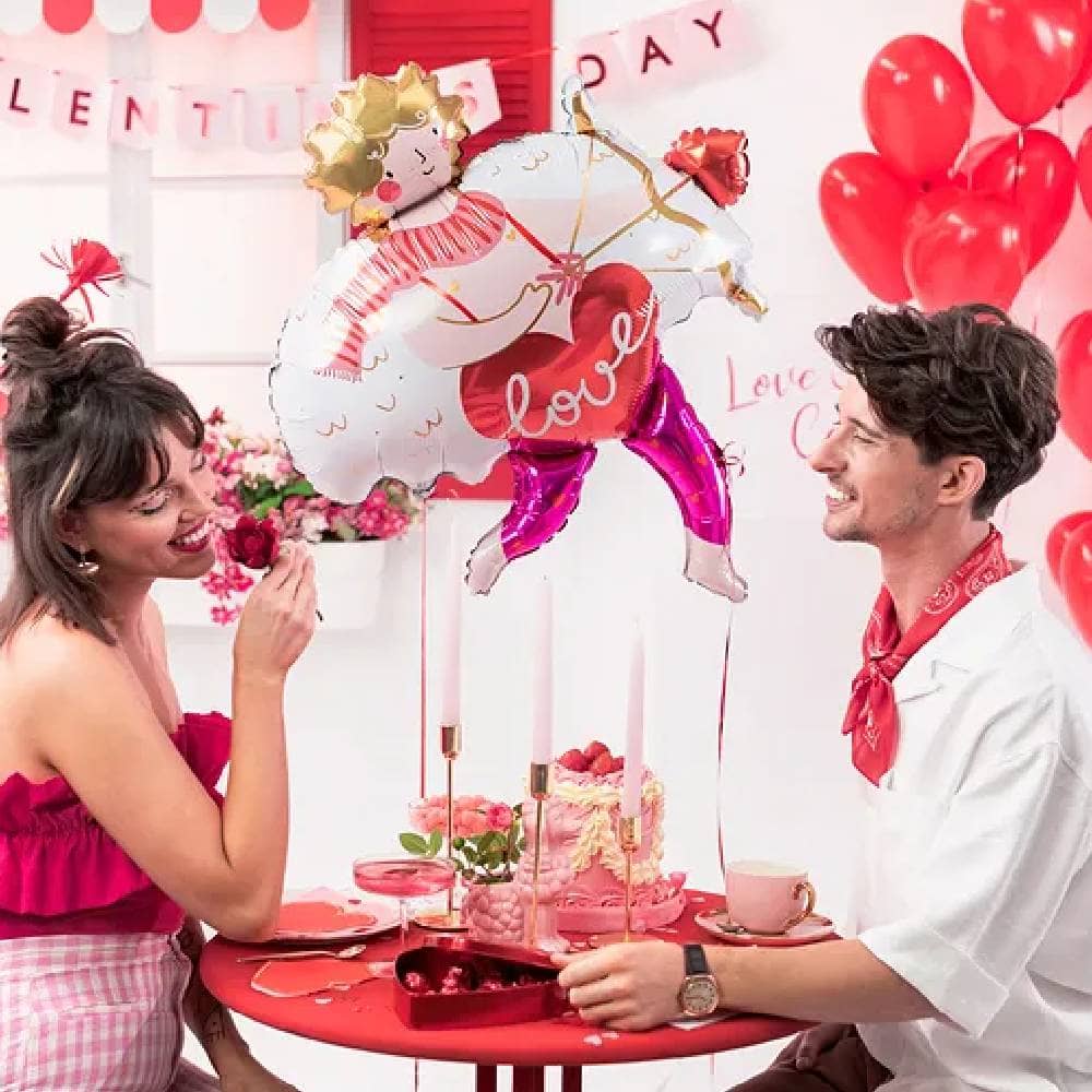 Man en vrouw aan een rode tafel met Valentijnsversiering in het rood en roze