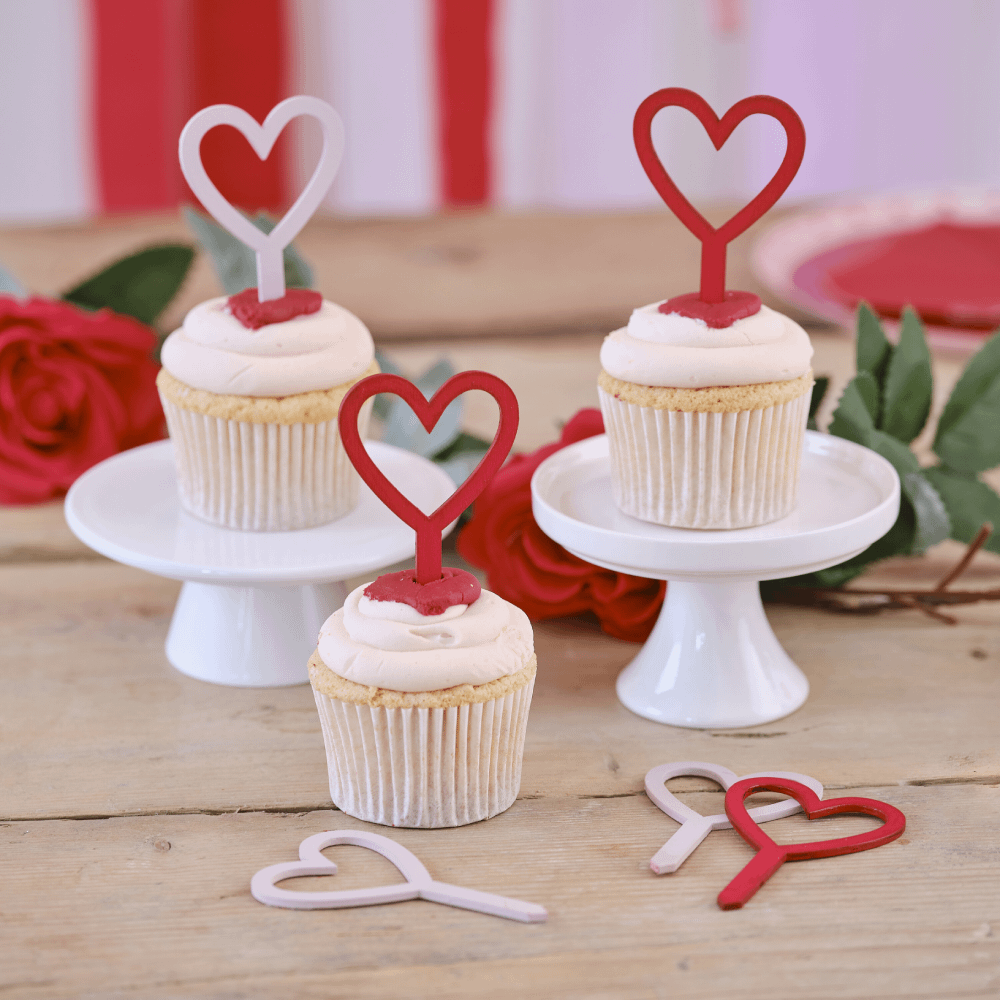 Cupcakes met roze en rode cupcaketoppers in de vorm van hartjes op een houten tafel