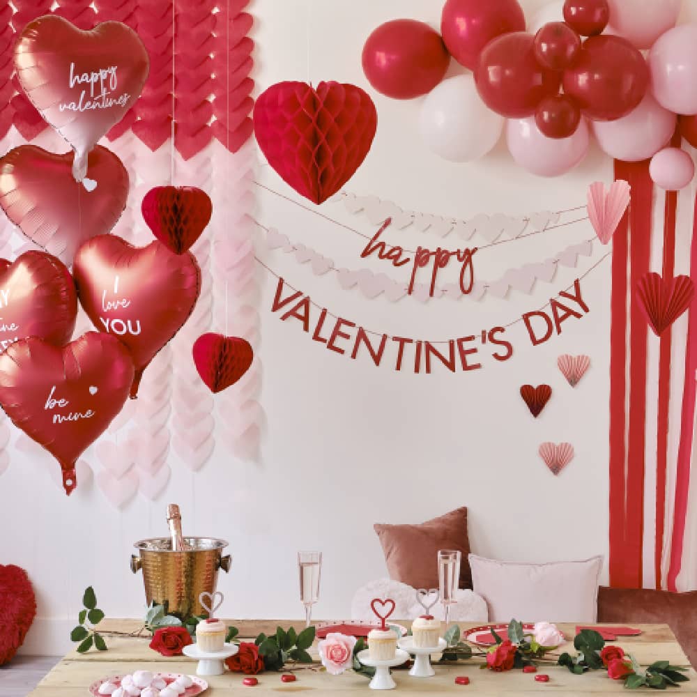 Rode Valentijnsversiering met hartvormige ballonnen en een ballonnenboog met streamers