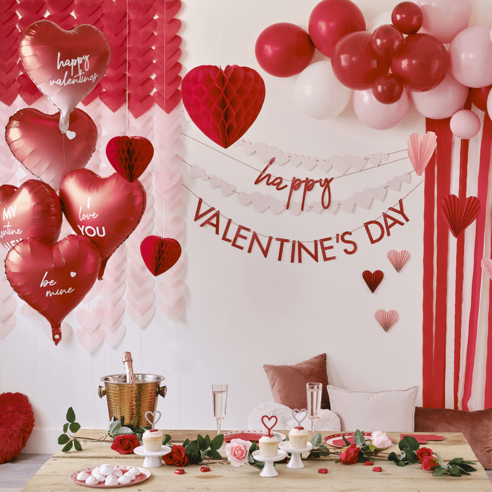 Rode Valentijnsversiering met hartvormige ballonnen en een ballonnenboog met streamers