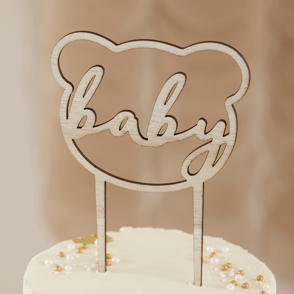 Houten taart topper in de vorm van een beer met de tekst baby in het midden op een beige taart